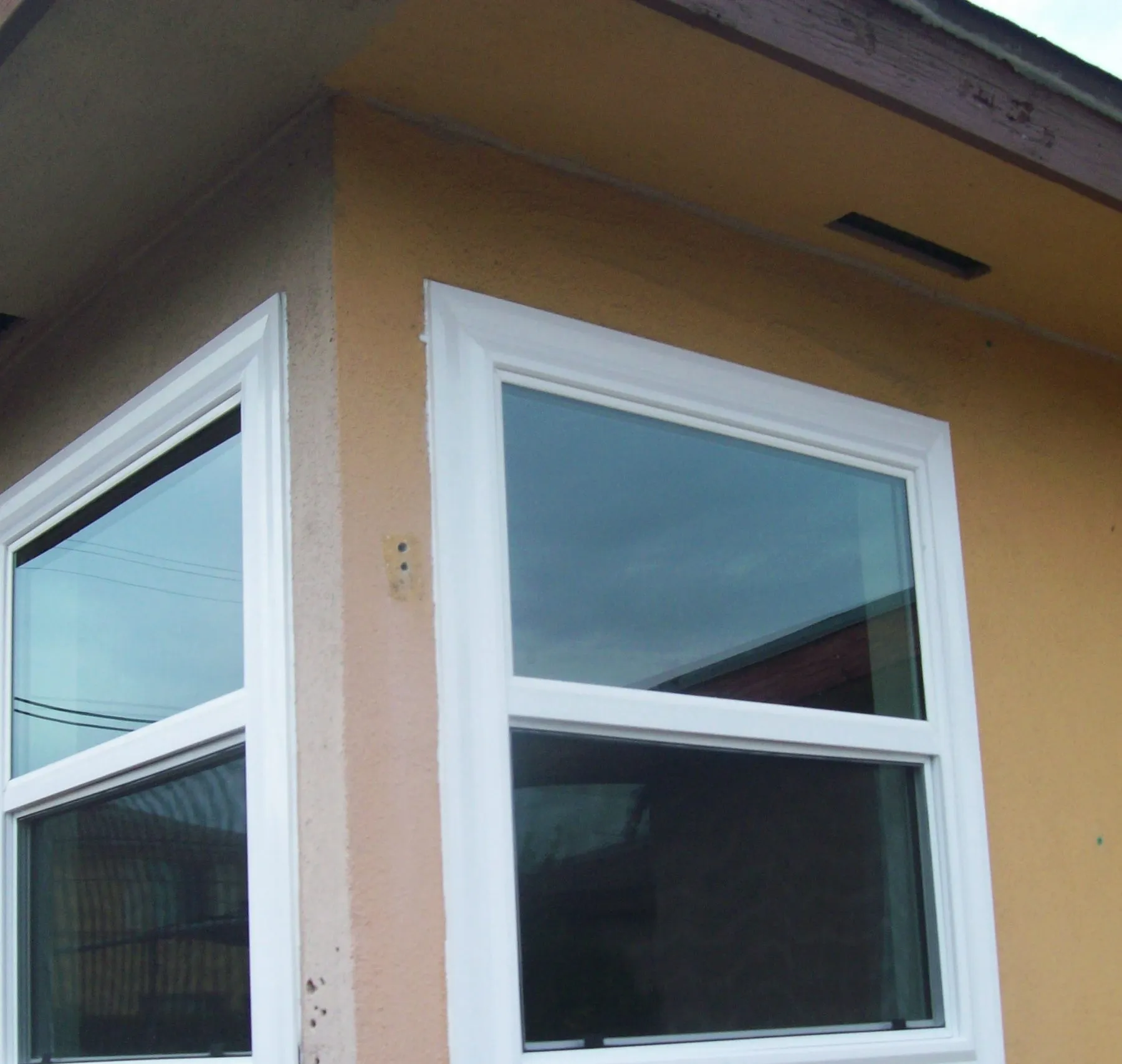 After: two windows on the same corner of a house before and after replacement