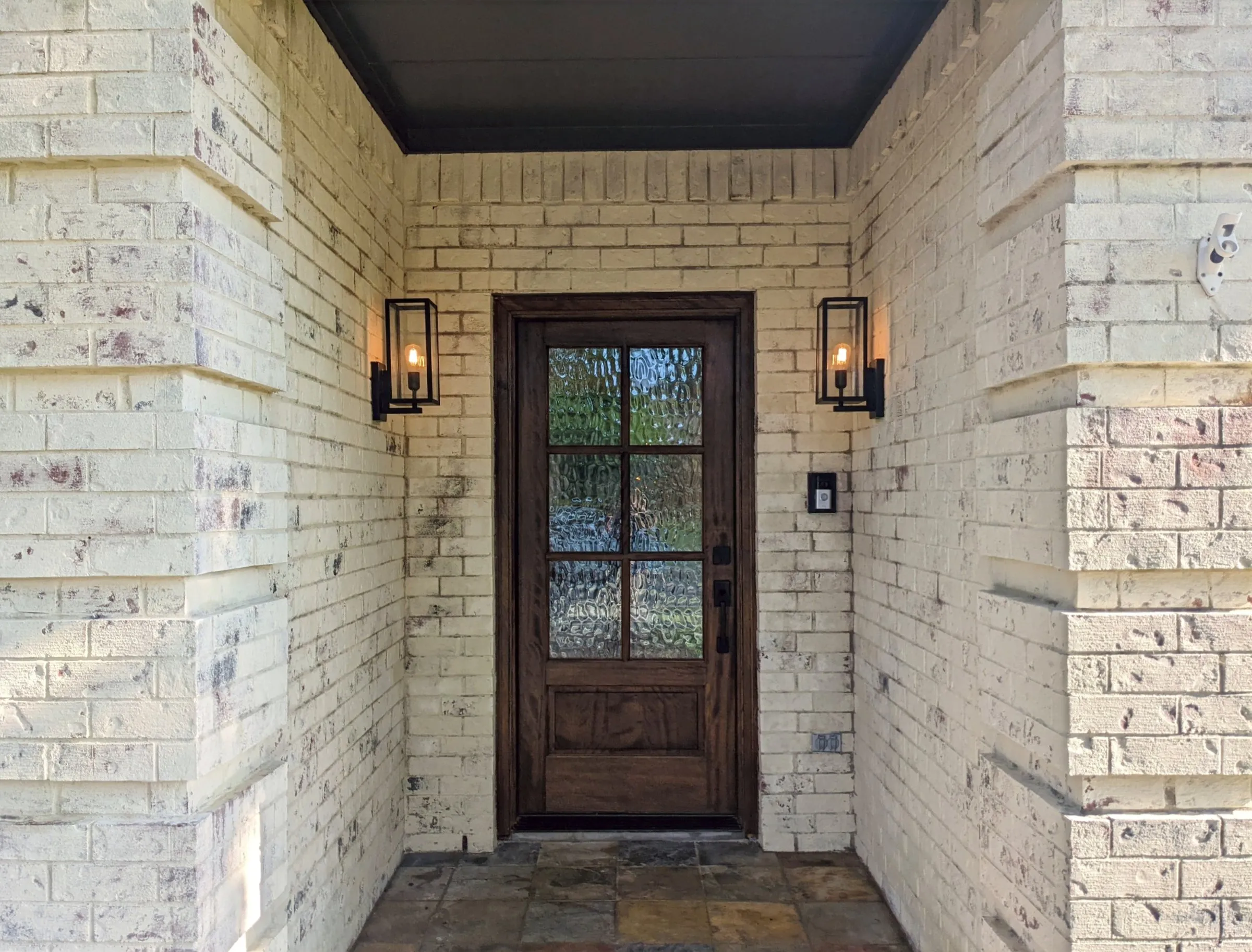 A finished craftsman entry door on a brick porch