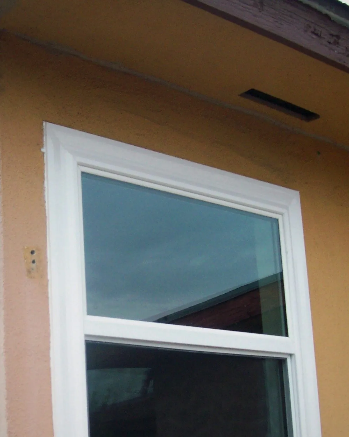 New white replacement windows on the warm stucco corner of a Riverside-area home