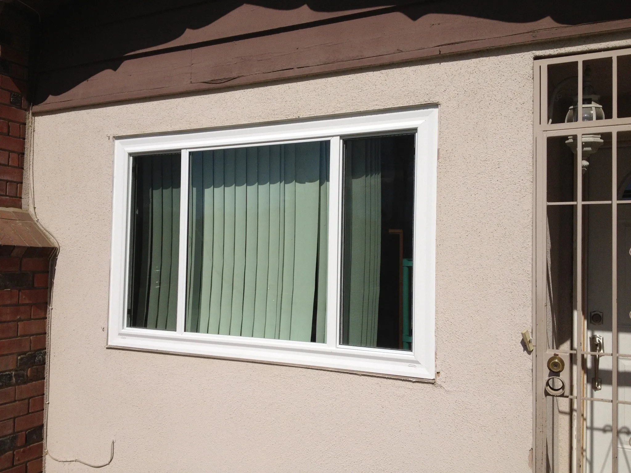A finished three-lite slider in a stucco wall on a Riverside-area home