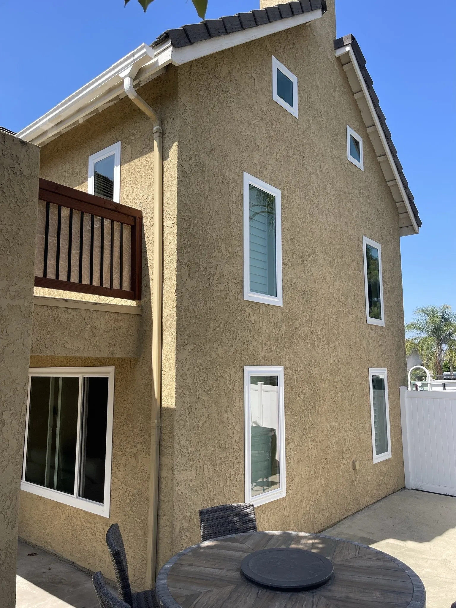 The corner of a tall house with several finished white replacement windows